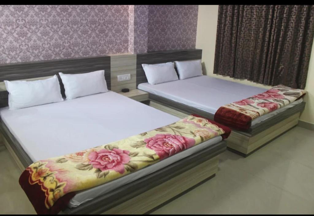 dwa łóżka w pokoju z kwiatami w obiekcie Hotel Srimanta sankardev w mieście Majuli