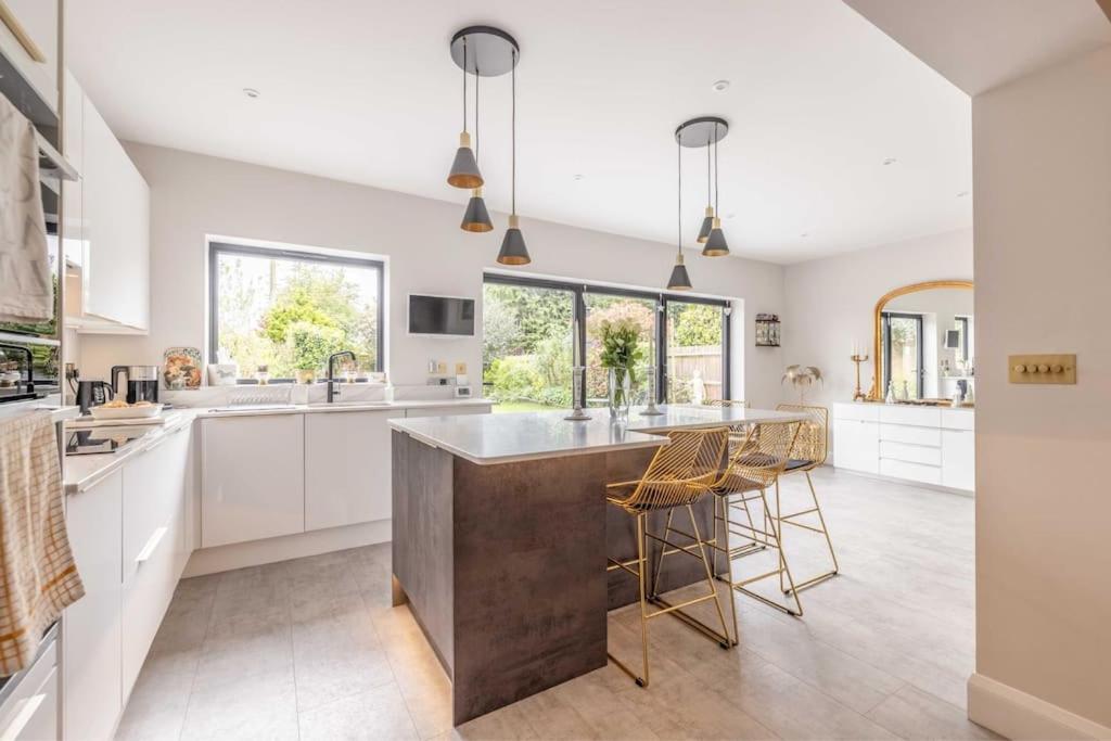 a kitchen with white cabinets and a large island with bar stools at Windsor Charm Spacious 3-Bed, Parking & Garden - By Tempstay in Windsor