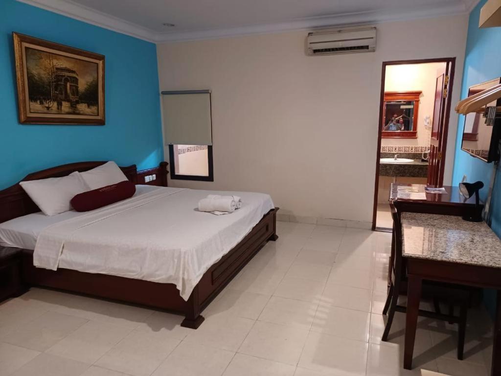 1 dormitorio con 1 cama con pared azul en 3 Putra BI Executive Hotel Jakarta, en Yakarta