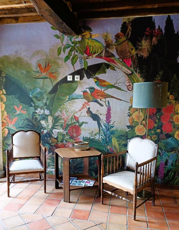 - deux chaises et une table devant une fresque dans l'établissement Clos Baroanni - Studio La Volière, à Terraube