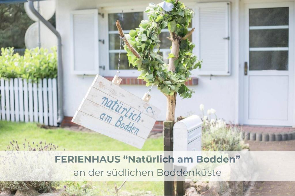 un cartel en un árbol delante de una casa en Ferienhaus NATÜRLICH AM BODDEN, en Michaelsdorf