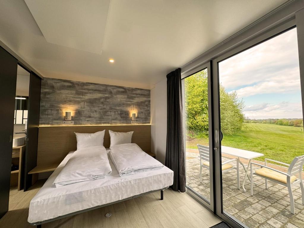 1 dormitorio con 1 cama y balcón con mesa en Golf Cubes Hohwacht en Hohwacht