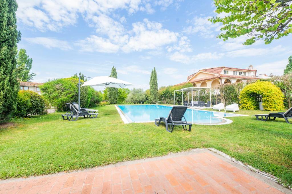 una piscina en un patio con 2 sillas y una sombrilla en Astonishing Villa with Pool and Garden, en Formello