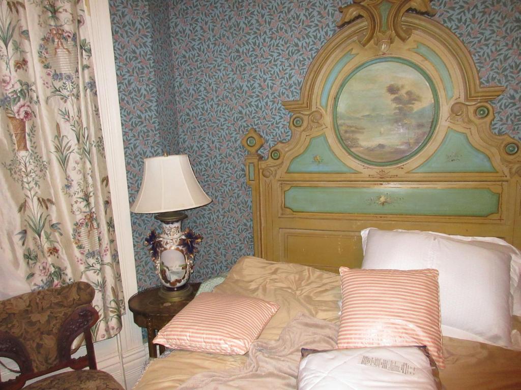 Schlafzimmer mit einem Bett mit einem großen Kopfteil in der Unterkunft Johnstone Mansion in Keokuk