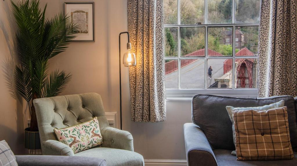 uma sala de estar com duas cadeiras e uma janela em Ironmasters House em Ironbridge