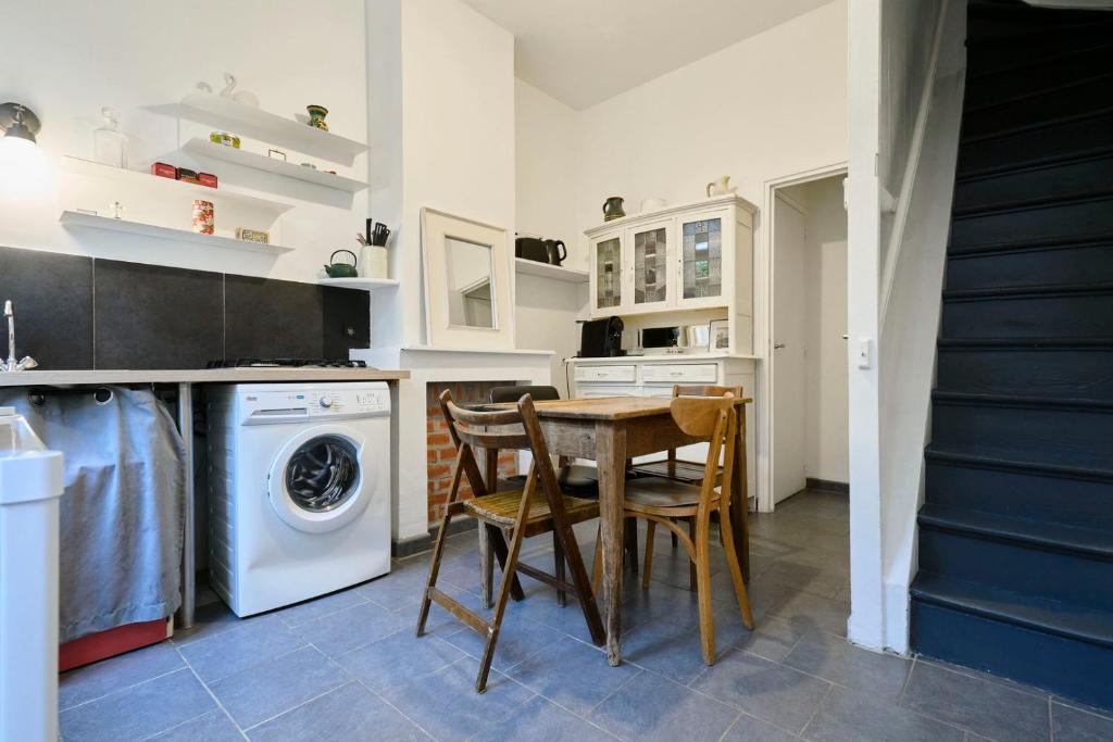 une cuisine avec une table et une machine à laver dans l'établissement Maisonnette atypique dans le vieux Lille, à Lille