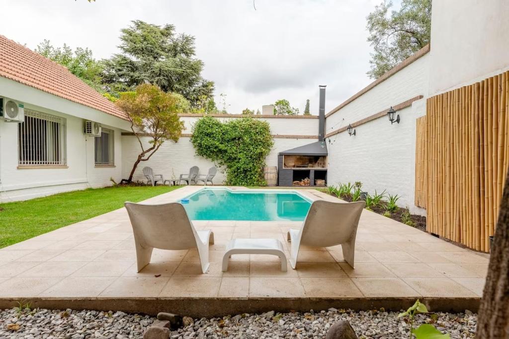 un patio con 2 sillas y una piscina en Casa Noble en Mendoza