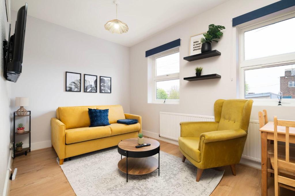 een woonkamer met 2 gele stoelen en een tafel bij 2 bedroom flat near Tottenham Hotspur Stadium in Londen