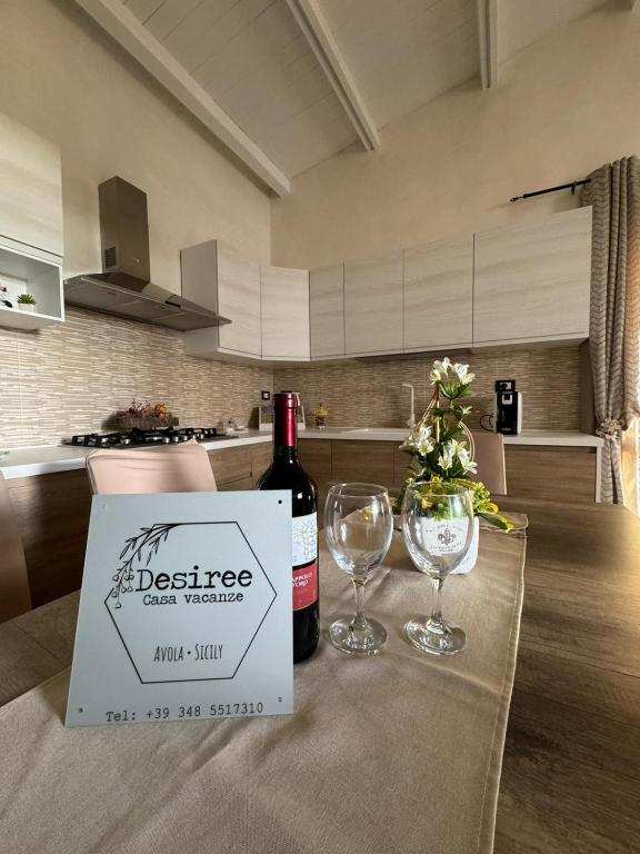 a bottle of wine and two glasses on a table at Desiree Casa Vacanze in Avola