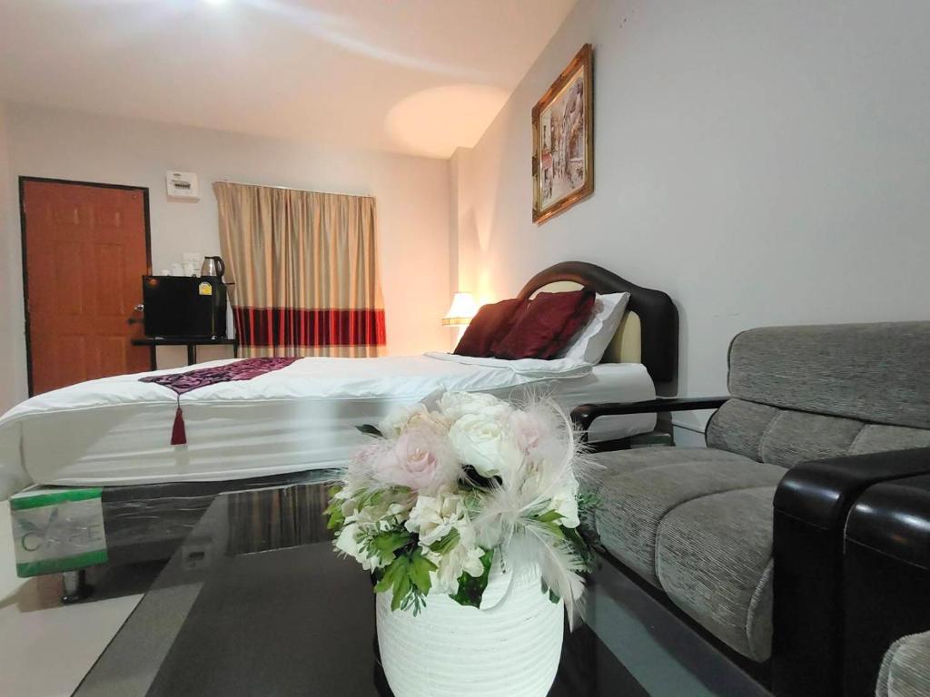 a hotel room with a bed and a table with flowers at the rich room ห้องพักนครราชสีมาใกล้เซ็นทรัล in Ban Pra Dok