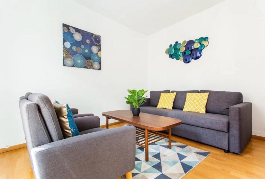 uma sala de estar com um sofá e uma mesa em 678 Suite Raspail - Superbe Appartement em Levallois-Perret