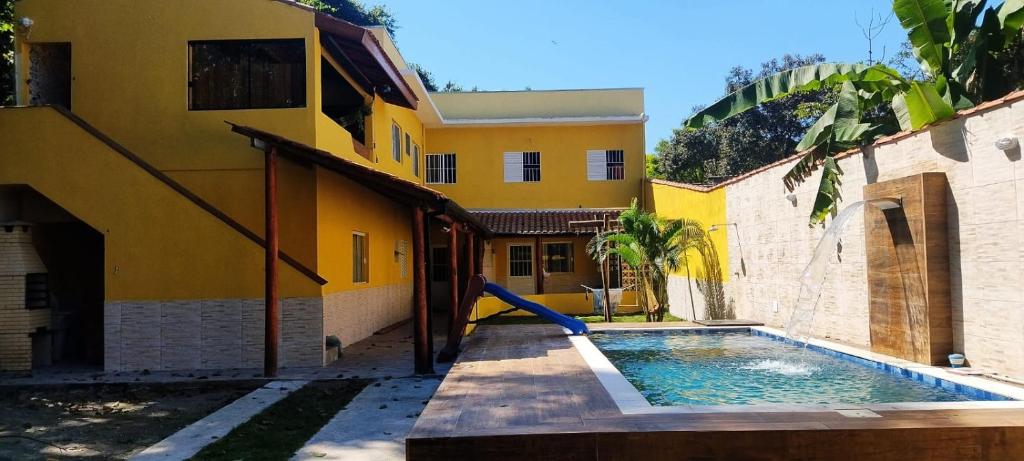 uma casa com piscina em frente a um edifício em casa condomínio próximo à praia em Caraguatatuba