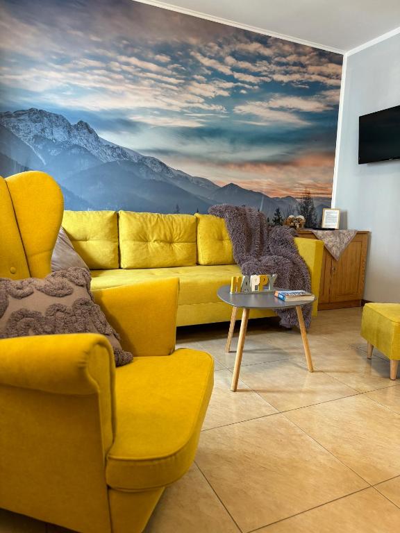 a living room with a yellow couch and a mountain mural at Zakopane - Apartament Chomikówka in Zakopane