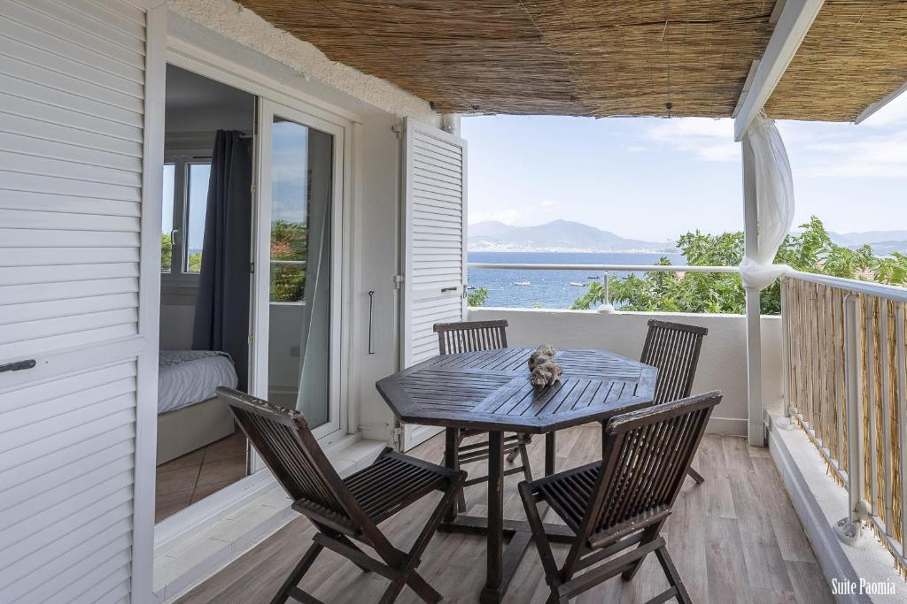 una mesa y sillas en un porche con vistas al océano en Paomia, en Grosseto-Prugna