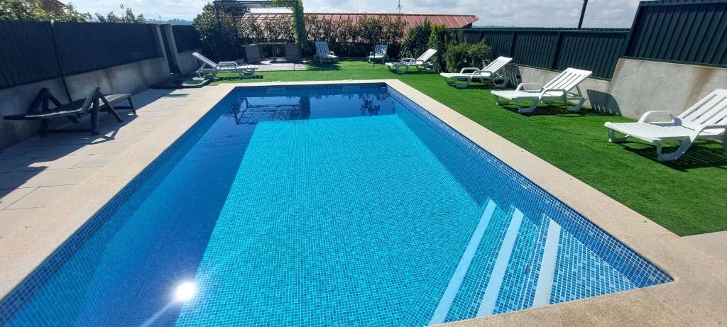 a swimming pool with chairs and a yard with a lawn at Varandas do Dão & Estrela in Pardieiros
