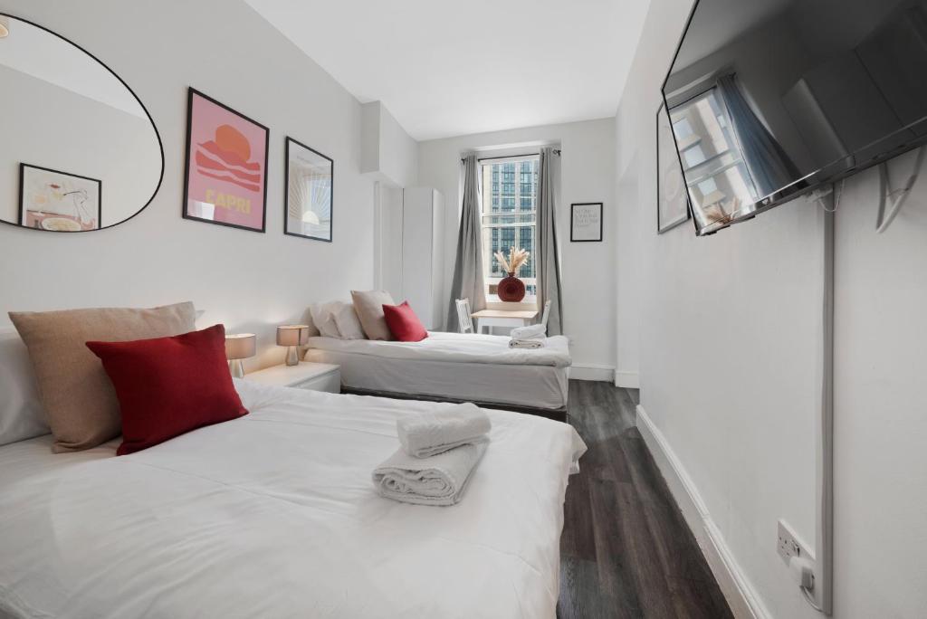 a white bedroom with two beds and a couch at Studio 2- Archway Station in London