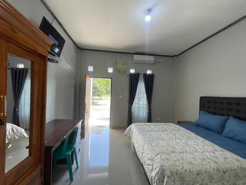 a bedroom with a bed and a desk and window at Sumbawa Maluk Homestay Kost tika in Maluk
