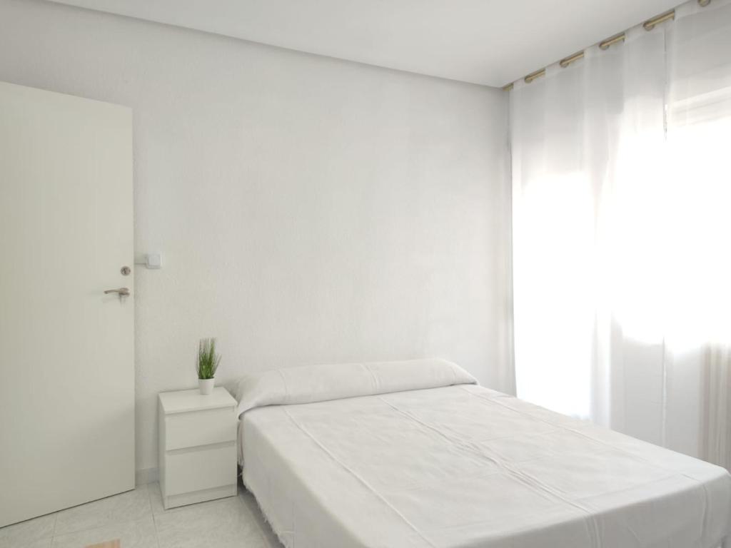 Habitación blanca con cama y ventana en JL Cristobal Lozano en Albacete