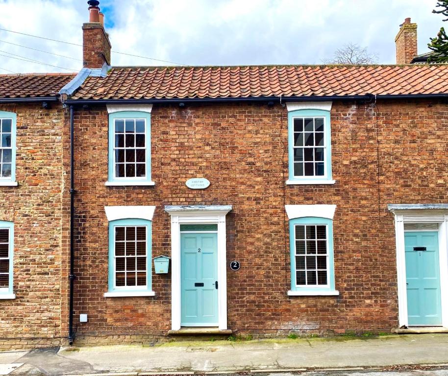 Barrow upon HumberにあるCharacterful 3 Bed cottage in Barrow upon Humberの青いドアと白い窓のあるレンガ造りの家
