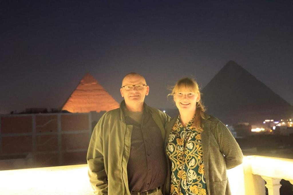 a man and a woman standing in front of pyramids at Explore Stars Pyramids View in Cairo