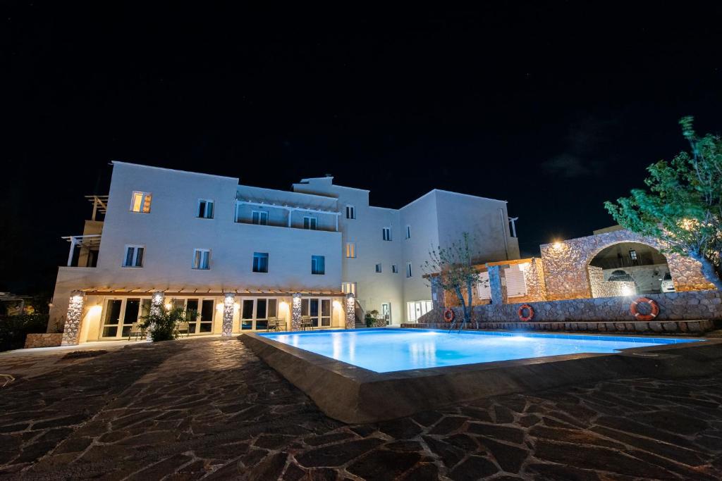 - un grand bâtiment blanc avec une piscine la nuit dans l'établissement GIN Wellness Hotel, à Pyrgos