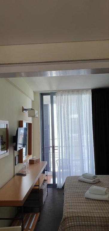 a bedroom with a desk and a bed and a window at Spetses Hotel in Spetses