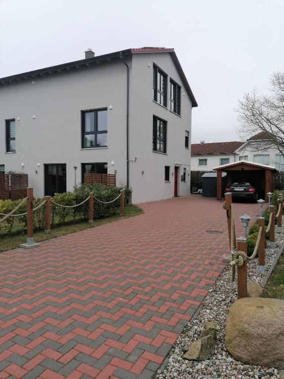 een wit huis met een rode bakstenen oprit bij Breeger Boddenblick in Breege