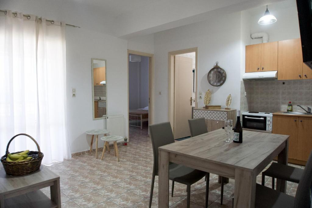 Blue Star Sea Apartment في أذيليانوس كامبوس: مطبخ وغرفة معيشة مع طاولة وكراسي خشبية