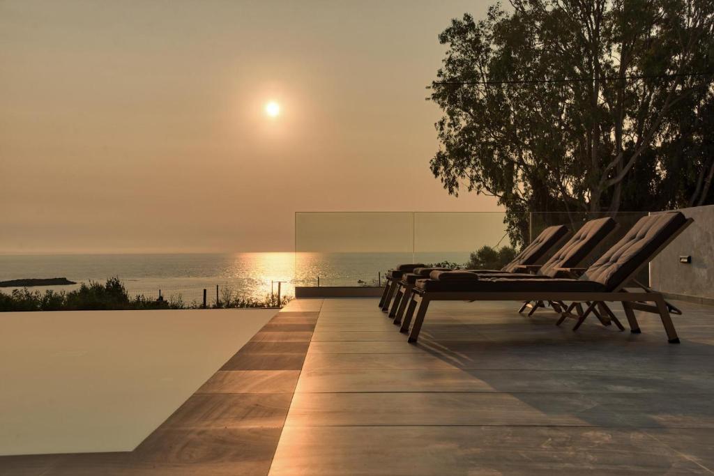 a row of chairs sitting on the edge of a swimming pool at Luxury Villa Mon II Vassilikos in Vasilikos