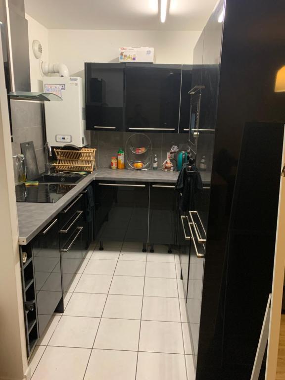 una cucina con armadi neri e pavimento piastrellato bianco di Cosy appartement T3 meublé Aubervilliers - La Plaine ad Aubervilliers