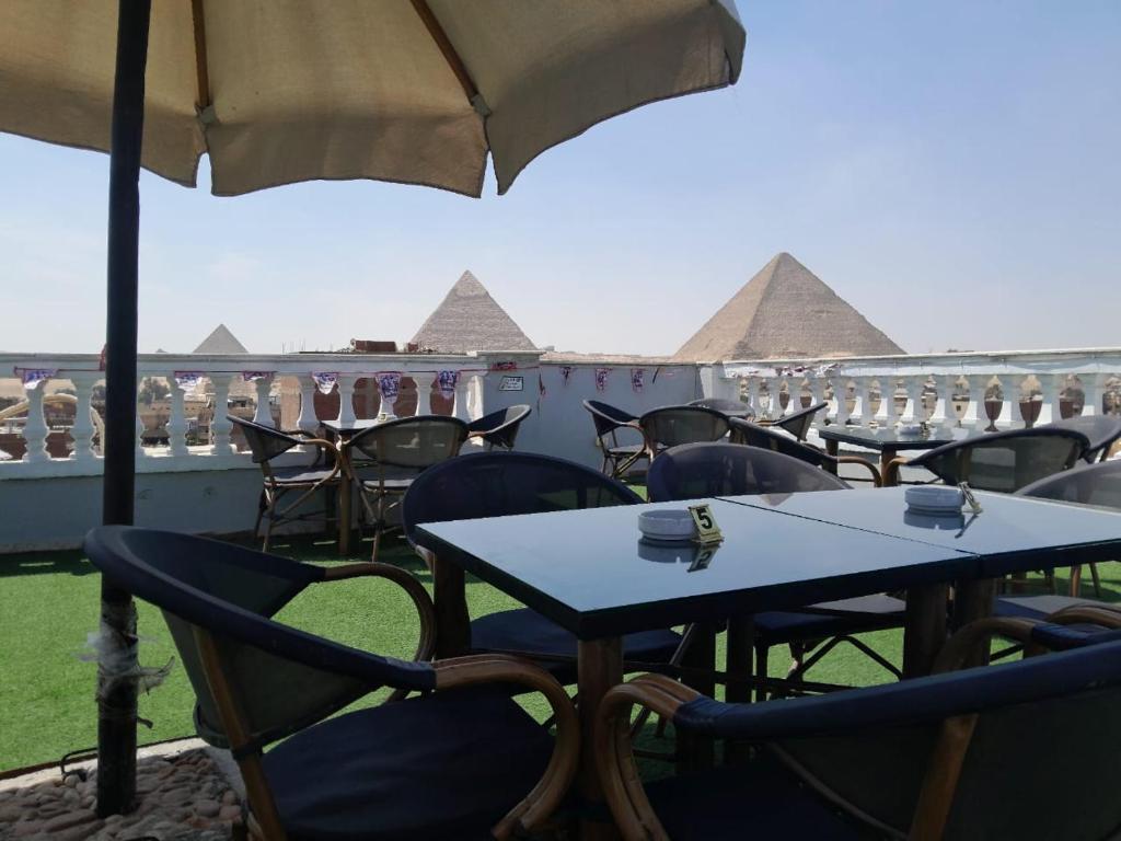 Explore Stars Pyramids View في القاهرة: مجموعة طاولات وكراسي مع الاهرامات في الخلفية