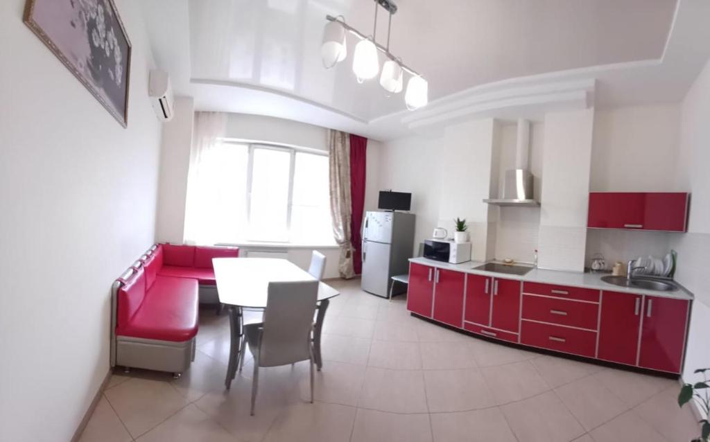 una cucina con armadi rossi e un tavolo in una stanza di Apartament na Panteylemonovskaya a Odessa