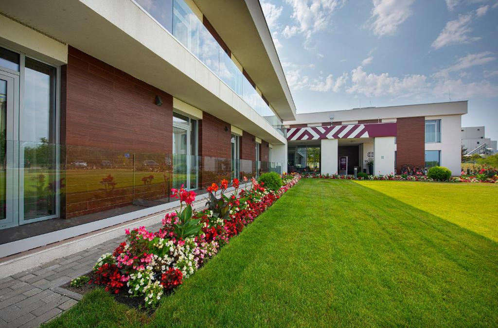 a building with a row of flowers in a yard at Outlet Hotel Polgár in Polgár