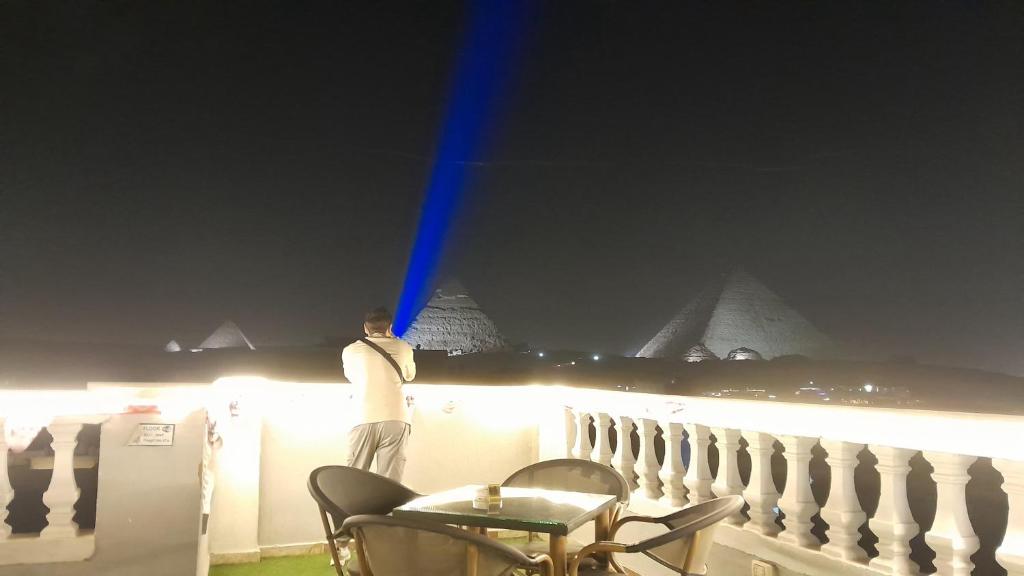 a man standing on a fence looking at the pyramids at Explore Stars Pyramids View in Cairo