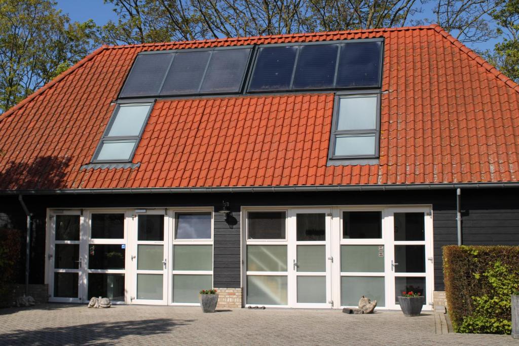 an orange roofed building with white doors and windows at Hoeve Hofwijk in Kamperland