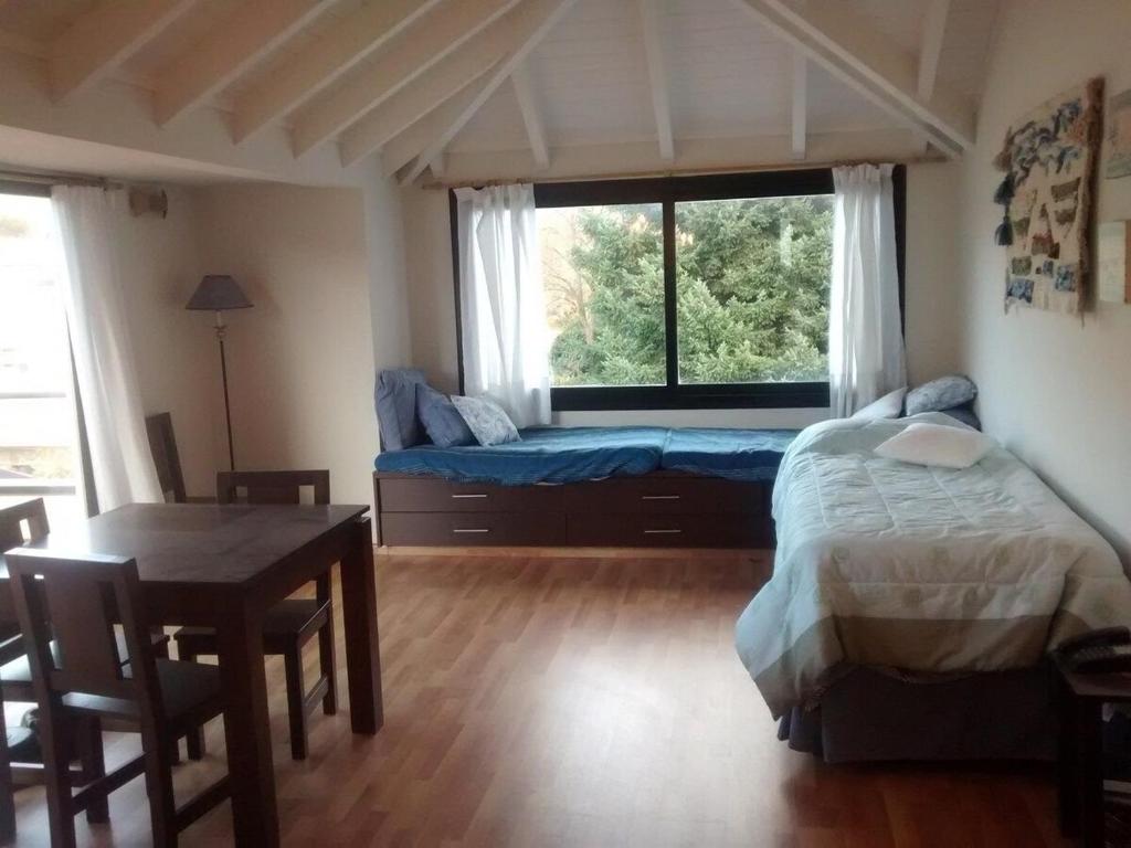 Schlafzimmer mit einem Bett, einem Tisch und einem Fenster in der Unterkunft Monoambiente céntrico equipado - AlquilaMiCasa in San Martín de los Andes