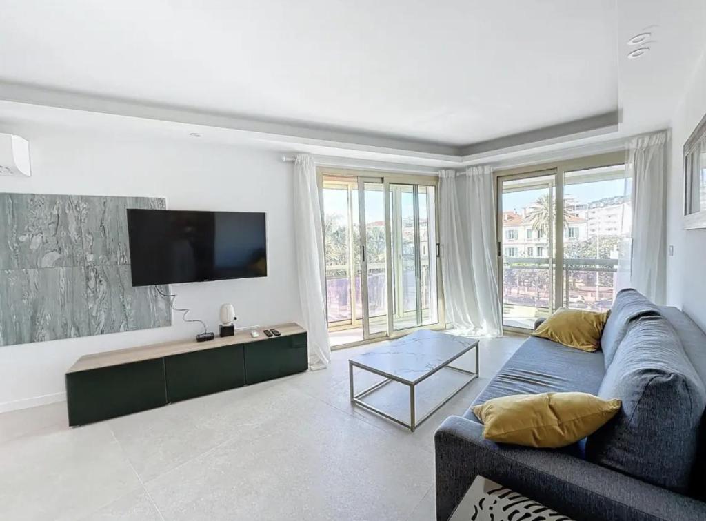 un salon avec un canapé bleu et une télévision à écran plat dans l'établissement Modern 2 Bedroom in the Heart of Cannes, à Cannes