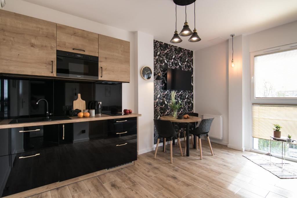 a kitchen with black cabinets and a table with chairs at Heron - 77 Apartments Wigury - Dostęp na KOD - Parking - Smaczna Kawa - Centrum - Blisko Piotrkowska - Galeria - Widok na miasto - Klimatyzacja - 7 piętro - FV in Łódź