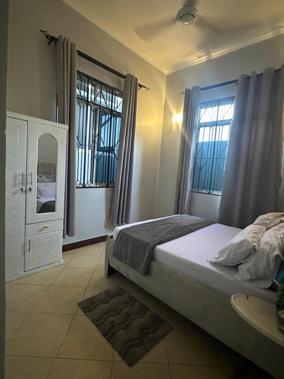 1 dormitorio con 1 cama grande y 2 ventanas en Stay with me 5, en Dar es Salaam