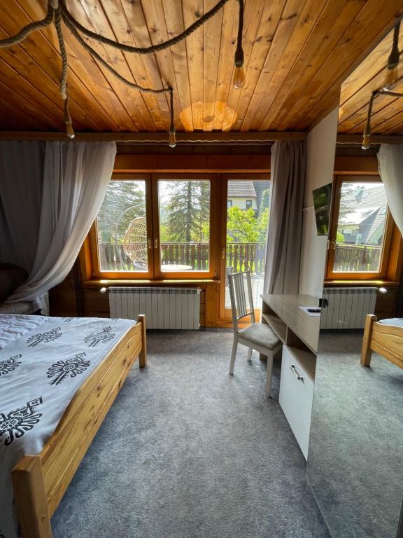 a bedroom with a bed and a desk and windows at Willa Antałówka in Zakopane