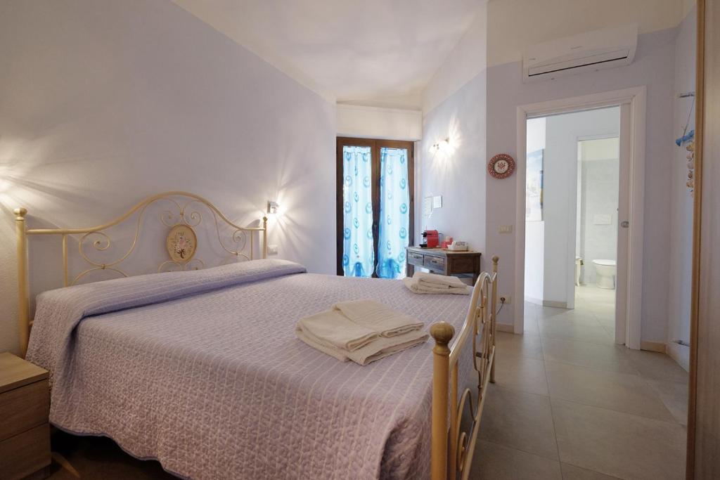 a white bedroom with a bed and a bathroom at CASA AZZURRA - BLUE HOUSE in Teulada