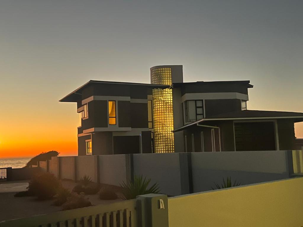 une maison sur la plage avec le coucher du soleil en arrière-plan dans l'établissement Beachfront Heaven, à Henties Bay