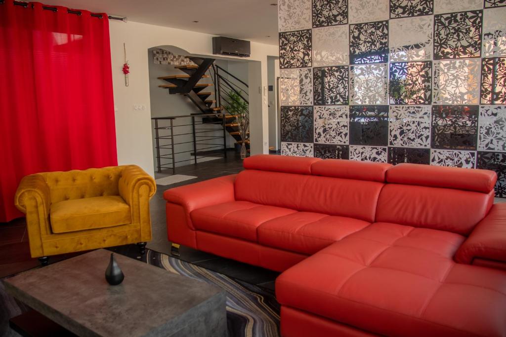 Loft de 2 Suites, Jacuzzi, Sauna et Massage في بلانياك: غرفة معيشة مع أريكة حمراء وكرسي