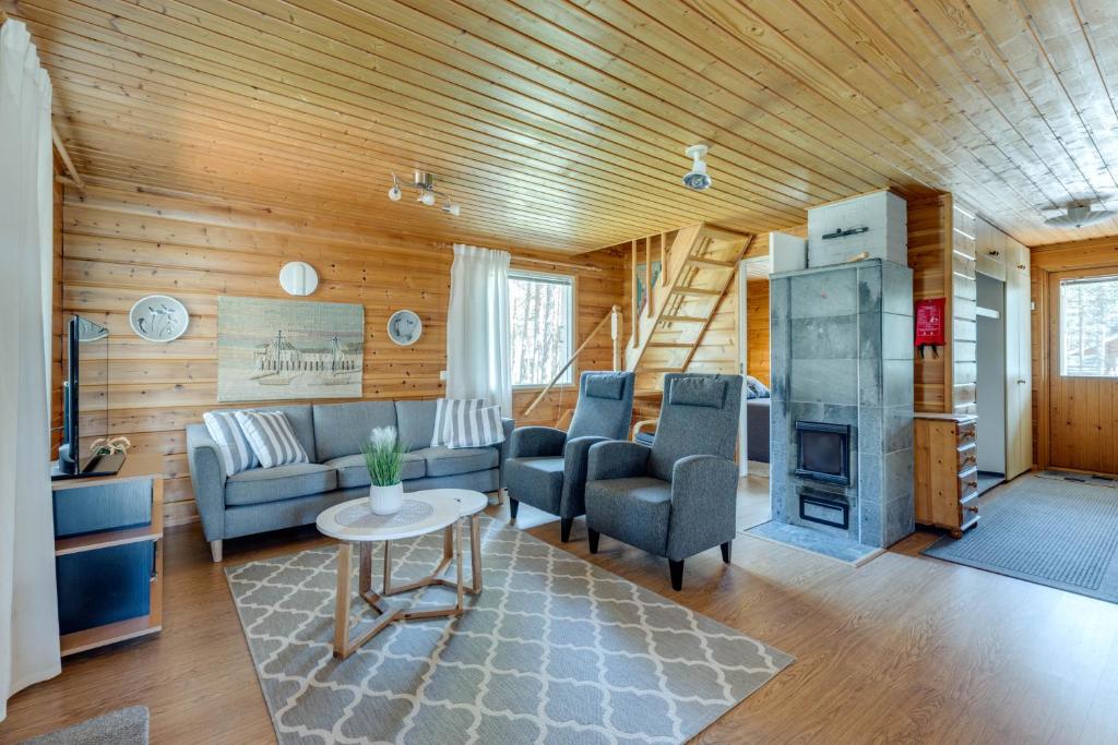 ein Wohnzimmer mit einem Sofa, Stühlen und einem Kamin in der Unterkunft Mehtämökki in Kalajoki