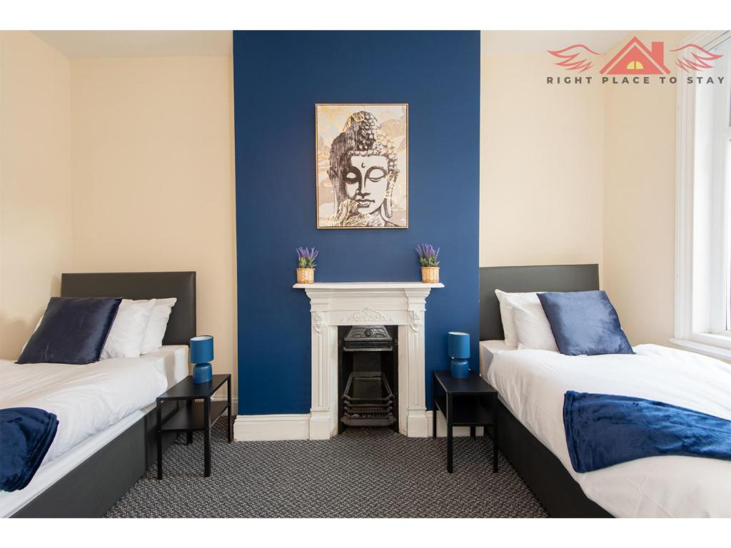 two beds in a room with blue walls and a fireplace at Feature 2Bed Terraced Home Near Airport and City Centre in Darlington