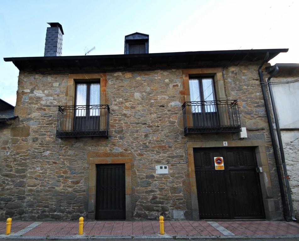 un antiguo edificio de piedra con 2 puertas y 2 balcones en Casa Magueto en Toreno