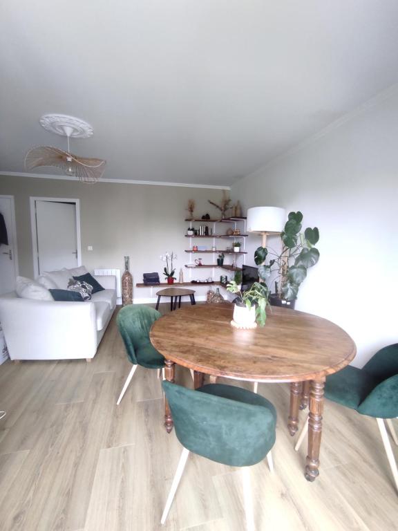uma sala de estar com uma mesa de madeira e cadeiras verdes em Apt calme, proche hôpital, centre ville em Brive-la-Gaillarde