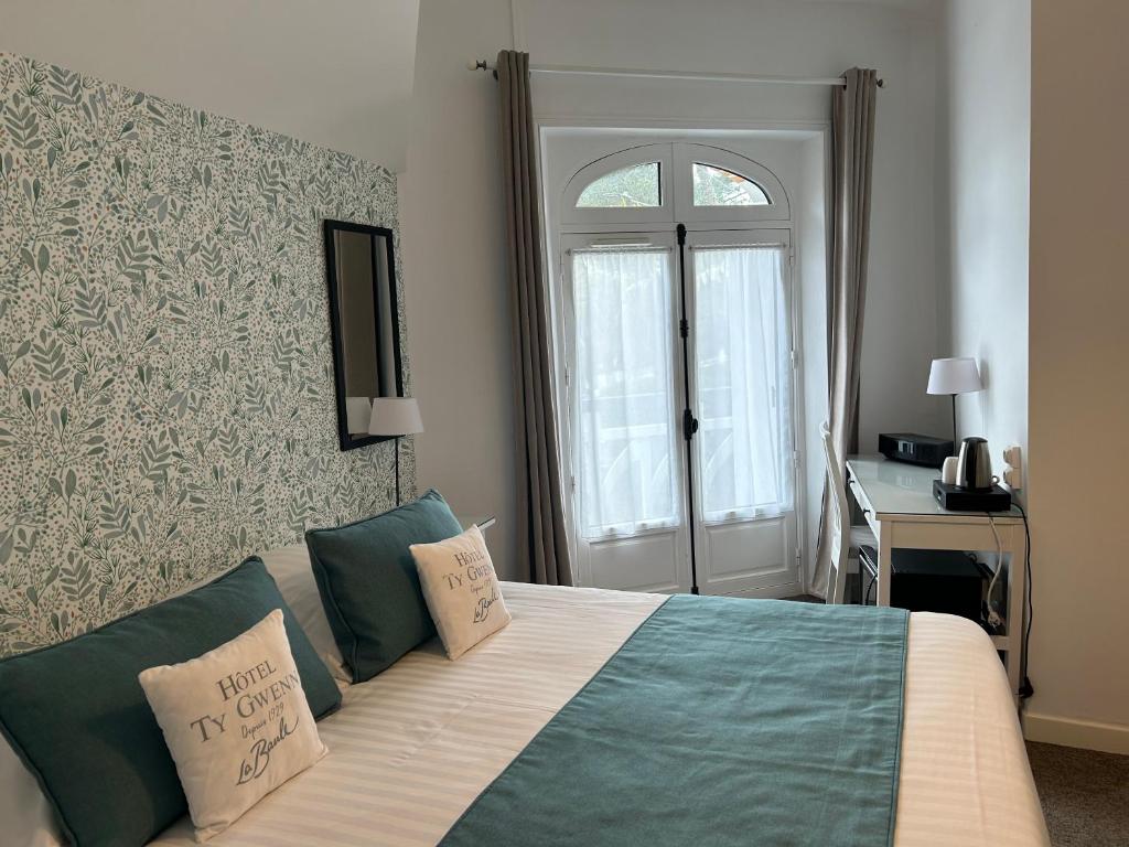 a bedroom with a bed and a desk and a window at Hotel Ty Gwenn La Baule in La Baule