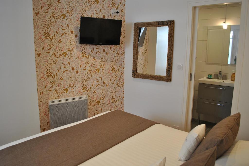 a bedroom with a bed and a television on a wall at Hotel Ty Gwenn La Baule in La Baule