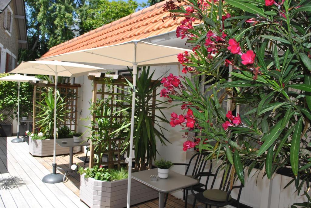 a patio with tables and chairs and pink flowers at Hotel Ty Gwenn La Baule in La Baule